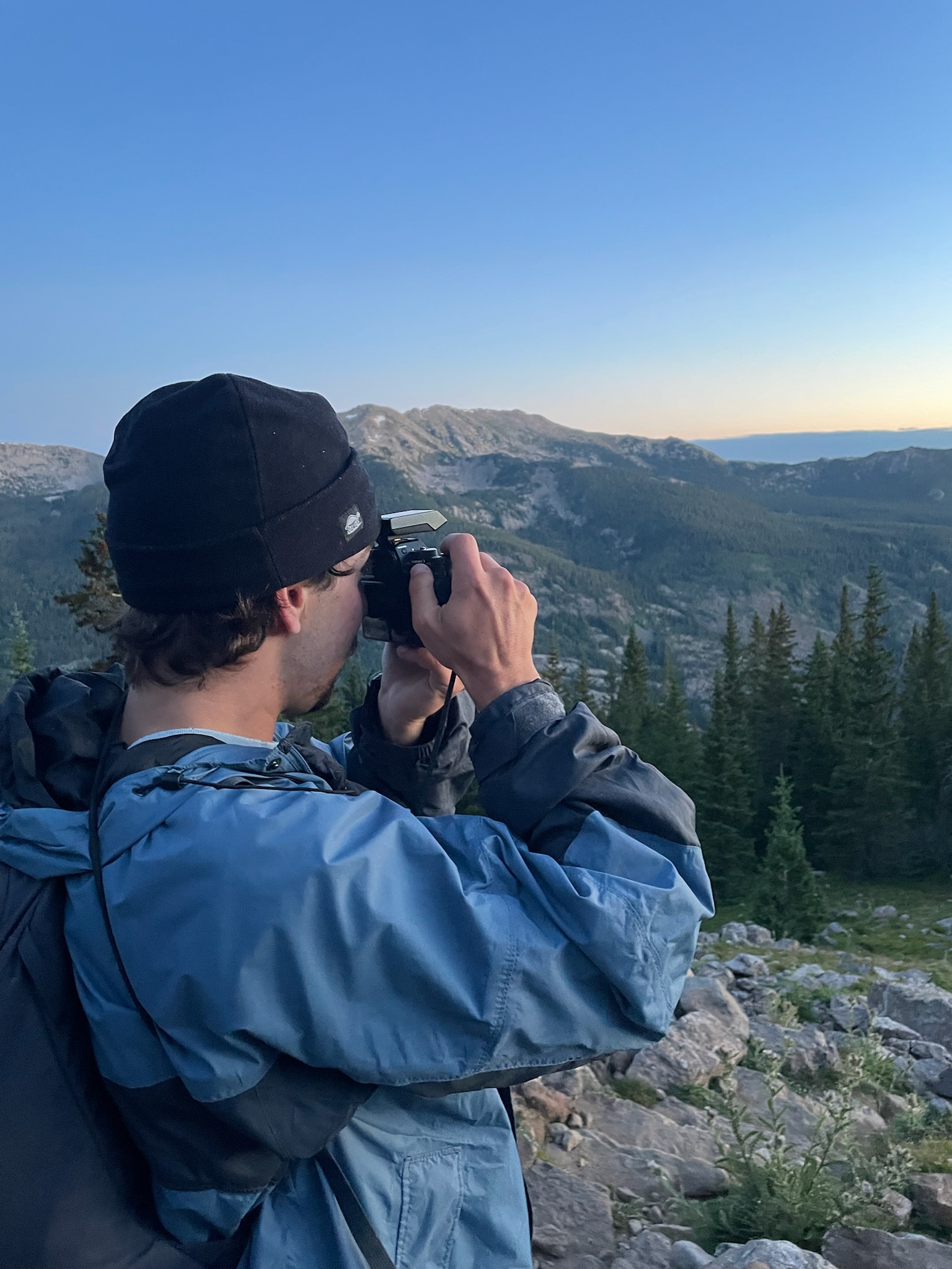 Santo photographing a mountain landscape at golden hour